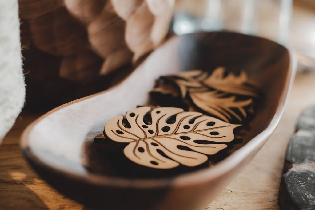 Hand-cut wooden monstera leaves in a carved bowl